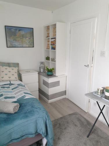 1 dormitorio con cama, mesa y puerta en Cosy & bright room en Loughborough