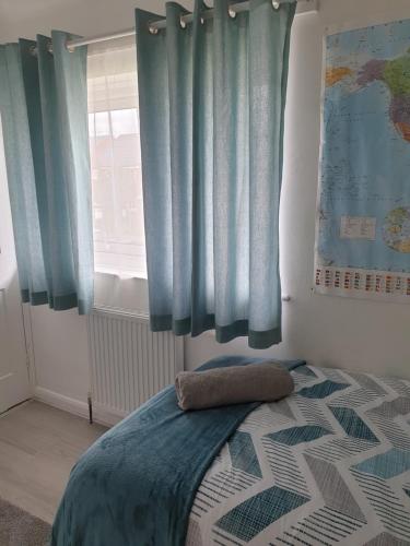 a bedroom with blue curtains and a bed and a window at Cosy & bright room in Loughborough