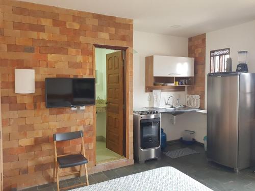 uma cozinha com uma parede de tijolos e um frigorífico em APART STUDIOS PONTAL em Ilhéus