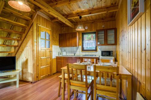 a kitchen with wooden walls and a table and chairs at Omega Domki in Gąski