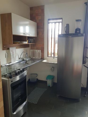 a kitchen with a stainless steel refrigerator and a window at APART STUDIOS PONTAL - Aeroporto 400 m - Centro 2,5 Km - Praia 1,5 Km in Ilhéus