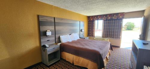 a hotel room with a bed and a window at Super 7 Inn in Midland