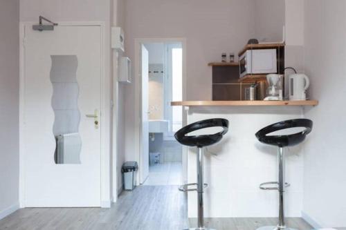 une cuisine avec deux tabourets noirs à côté d'un comptoir dans l'établissement LAYTON - A 2 min de la plage, du sillon et d'Intra muros !, à Saint-Malo