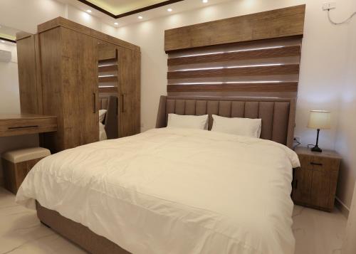 a bedroom with a large white bed with a wooden headboard at Amman in Amman