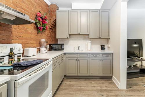 une cuisine avec des placards blancs et un mur en briques dans l'établissement James St Apartment Unit - Sleeps 6, à Hamilton