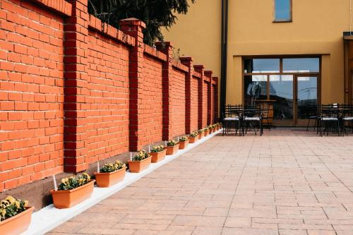 a brick wall with potted plants and tables and chairs at Pansion Mihića dvori in Babina Greda