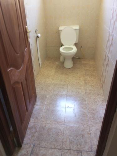 a bathroom with a toilet and a tiled floor at Annex in Kakamega