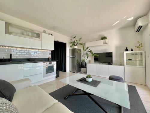 - une grande cuisine blanche avec une table dans une pièce dans l'établissement Studio 3 étoiles vue mer - terrasse - plage, à Vallauris