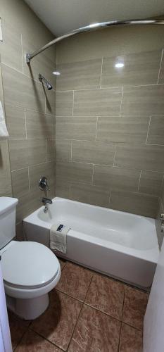 a bathroom with a toilet and a white bath tub at Super 7 Inn in Midland