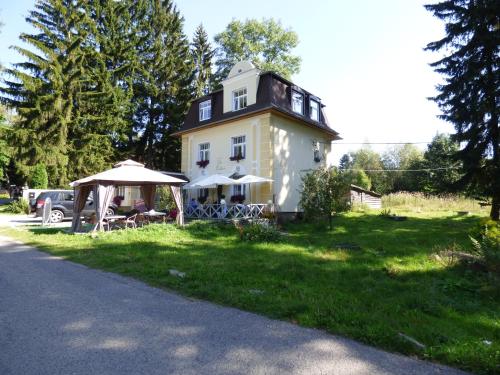 a house with a table and umbrellas in front of it at Villa Meteor in Mariánské Lázně