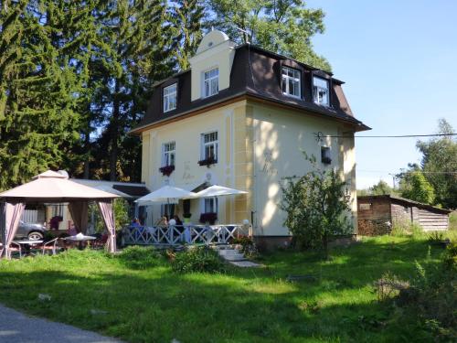 a house with tables and umbrellas in front of it at Villa Meteor in Mariánské Lázně