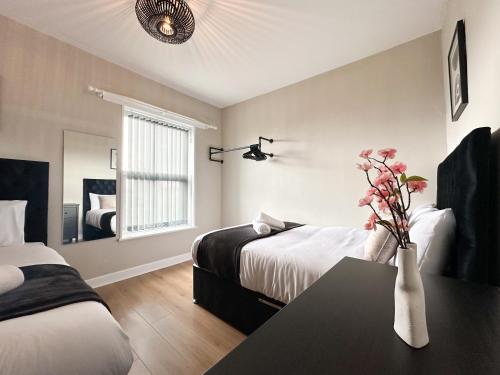 Una habitación de hotel con dos camas y una mesa con flores. en 2 Bedroom house 10 mins to City Centre & Albert Dock, en Liverpool