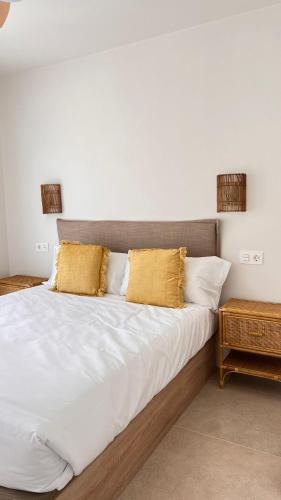 a bed with white sheets and yellow pillows at Olcina apartments in El Castell de Guadalest