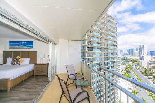 1 Schlafzimmer mit einem Bett und 2 Stühlen auf einem Balkon in der Unterkunft Ilikai Tower 1717 City View 1BR in Honolulu