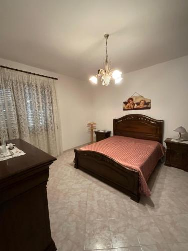 una camera con letto, tavolo e lampadario a braccio di Casa Doria a Tiggiano