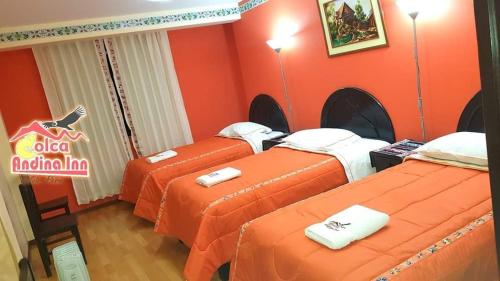 three beds in a room with orange walls at Colca Andina Inn Chivay in Chivay