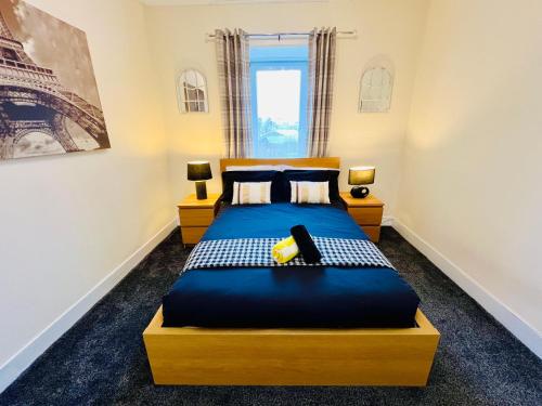 1 dormitorio con cama con sábanas azules y ventana en Cosy Apartment Glasgow Airport, en Paisley