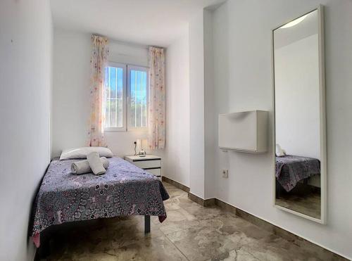 a small bedroom with a bed and a mirror at 3 bed ground first floor apartment. Close to beach in Mar de Cristal