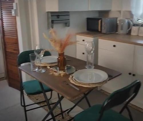 a table with plates and glasses and chairs in a kitchen at Grand Vue Apartment Vieux Fort in Vieux Fort