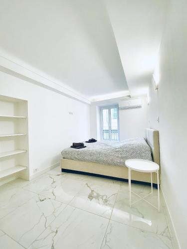 une chambre blanche avec un lit et une table dans l'établissement T3 carré d’or plein centre, à Nice
