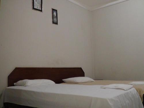 - une chambre avec 2 lits avec des draps blancs et 2 photos sur le mur dans l'établissement HOTEL NEW´S BUSINESS, à Macapá