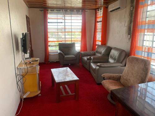 ein Wohnzimmer mit einem Sofa und einem TV in der Unterkunft Hotel La Rochelle in Bonamakolo