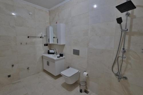 a white bathroom with a toilet and a shower at Yellow Stone House in Goreme