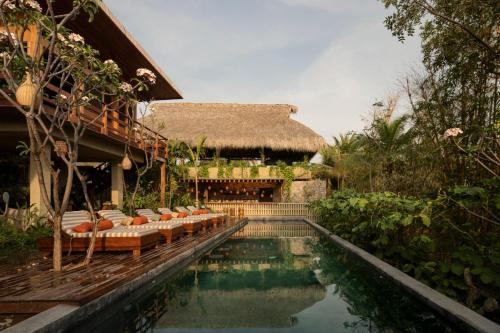 a resort with a swimming pool with chairs and a building at Ennea Hotel - Adults Only in Puerto Escondido