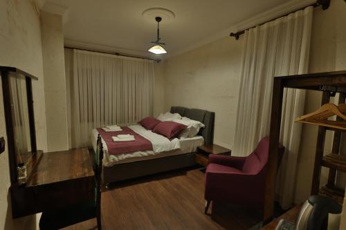 a small bedroom with a bed and a chair at Yellow Stone House in Goreme