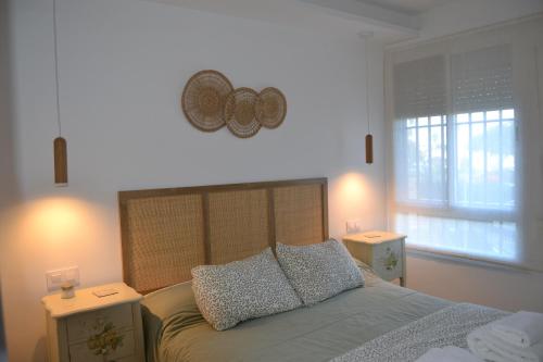 a bedroom with a bed with two night stands and two windows at Beach House Sotogrande - Torreguadiaro in San Roque