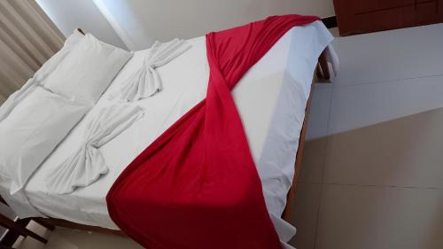 a bed with a red and white blanket on it at POUSADA BRASÃO in Governador Valadares