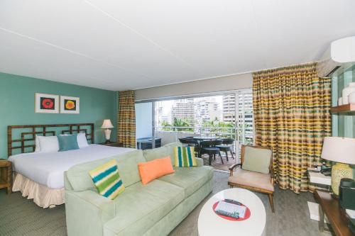 een slaapkamer met een bed en een woonkamer met een bank bij Ilikai Tower 613 City View 1BR in Honolulu