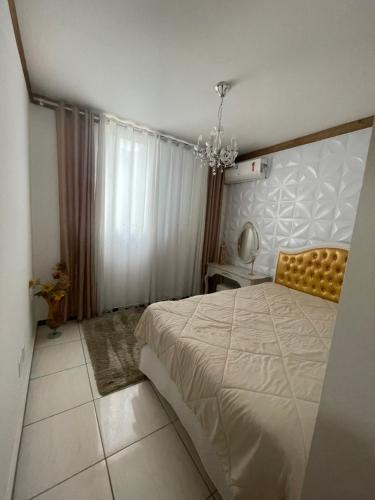 a bedroom with a large bed and a chandelier at Apart Governador Valadares in Governador Valadares