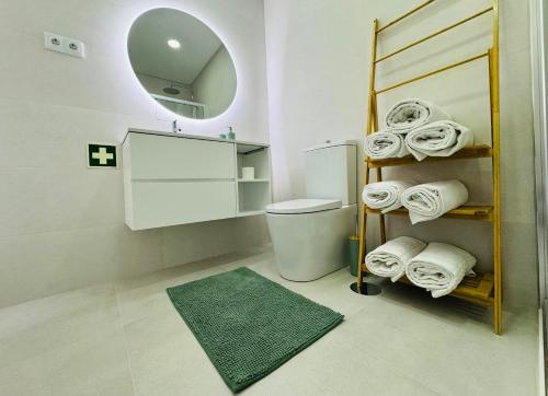 a bathroom with a toilet and a mirror and towels at Central Tiled Apartment in Aveiro