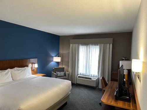 a hotel room with a bed and a desk and a window at Comfort Inn & Suites Akron South in Akron