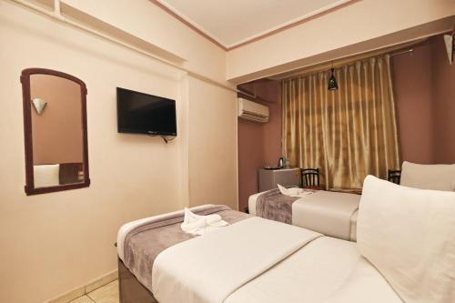 una camera d'albergo con due letti e uno specchio di Abo Elwafa Hotel a Sohag