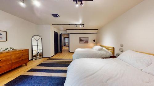 a bedroom with two beds and a dresser and a mirror at The Stone Mason - Large Modern Home on 5 Acres - 2 Hrs from NYC in Pond Eddy