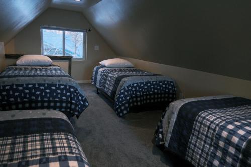 a attic room with three beds and a window at Chinook Wind Cabins in Talkeetna