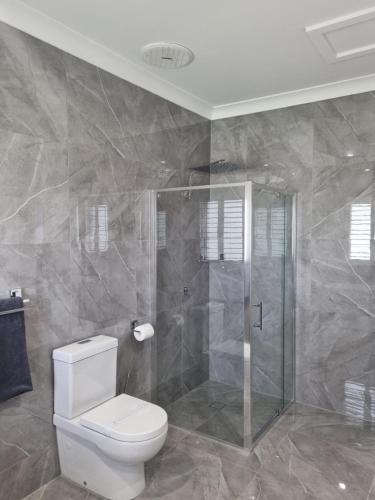 a bathroom with a toilet and a glass shower at Australian Homestead Motor Lodge in Wagga Wagga