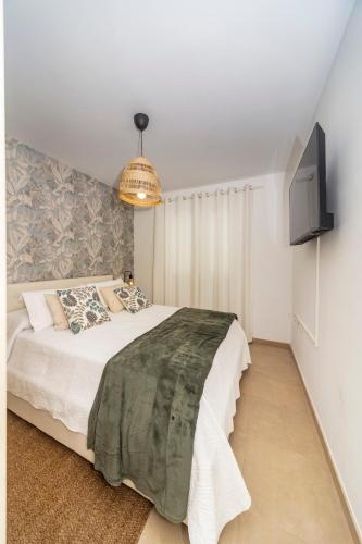 a bedroom with a bed and a tv on a wall at Luxury Apartment Chalana in Playa Honda