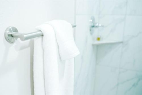 un baño con toallas blancas colgando de una puerta en Holborn Home: Find Iconic London, en Londres