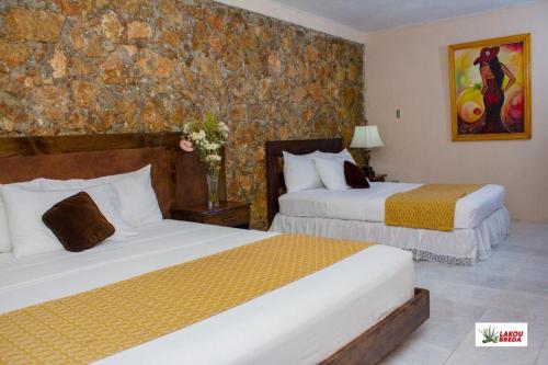 a hotel room with two beds and a stone wall at Lakou Breda in Cap-Haïtien
