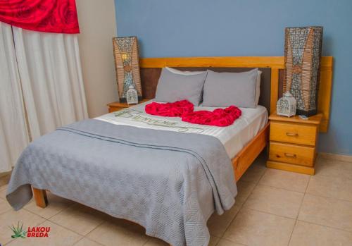 a bedroom with a bed with red roses on it at Lakou Breda in Cap-Haïtien