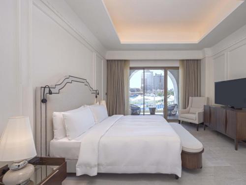 una camera bianca con un grande letto e una televisione di Town house residency 4 a Doha