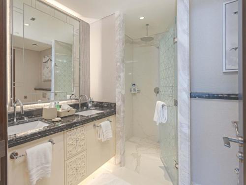 bagno con doccia, lavandino e specchio di Town house residency 4 a Doha