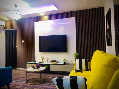 uma sala de estar com um sofá amarelo e uma televisão de ecrã plano em willy-richy Apartments em Ikeja