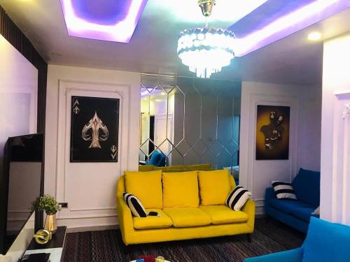 uma sala de estar com um sofá amarelo e um lustre em willy-richy Apartments em Ikeja
