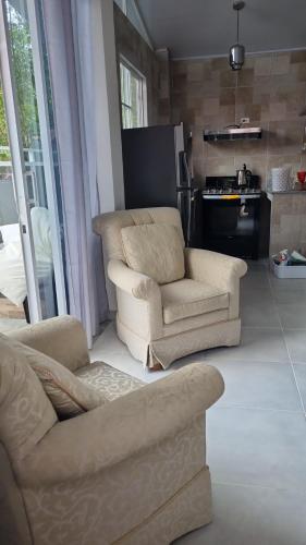 ein Wohnzimmer mit 2 Stühlen und einem Sofa in der Unterkunft Villa Helena in Los Altos de Cerro Azul