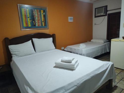 a bedroom with two beds with white towels on them at Pousada Alforria in Búzios