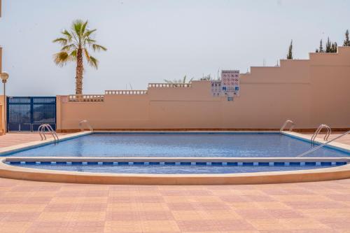 una piscina en un edificio con una palmera en Apartamento Las Brisas, Atico, en Puerto de Mazarrón
